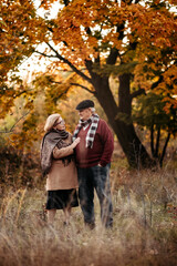 Elderly man lovingly looks at his elegant pensioner, hugs and enjoys her beauty, senior married couple dancing in autumn park, celebrating anniversary, affection