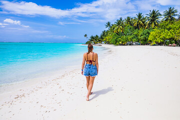 The girl is walking on a paradise island with turquoise water and exotic vegetation - the Maldives