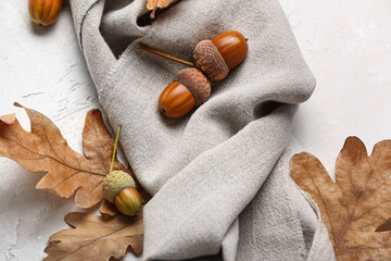 Oak acorns, dry leaves and fabric on light background, closeup