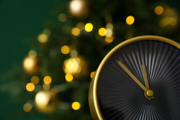 Stylish alarm clock on blurred Christmas tree background