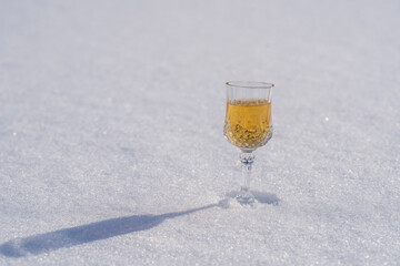 Homemade fruit tincture in a wine crystal glass on a snow and white background in winter