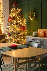 Dining table with burning candle in kitchen decorated for Christmas