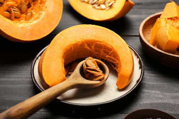 Plate with piece of pumpkin and seeds on dark wooden background, closeup