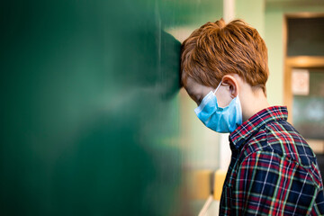 Schoolchildren wearing face masks in classroom. Impact of Covid-19 pandemic on schools and learning loss due to school closures during coronavirus.