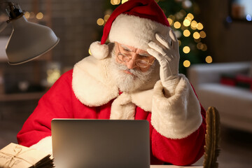 Santa Claus using laptop at home on Christmas eve