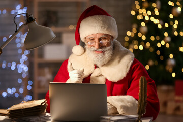 Santa Claus using laptop at home on Christmas eve