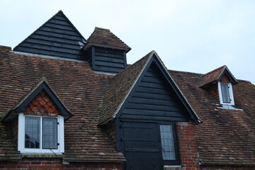 Fototapeta na wymiar Old English roof with roof tiles and wooden details and windows