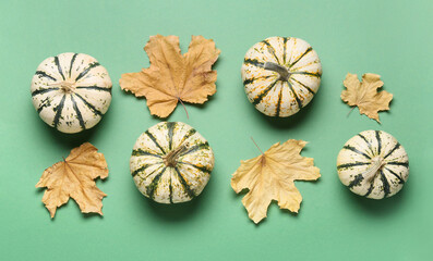 Whole fresh pumpkins with dried leaves on green background