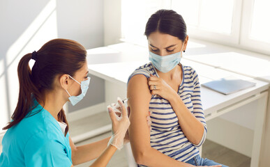 Obraz premium Nurse vaccinate female patient wearing mask in private clinic or hospital. Doctor give vaccination shot against covid-19 infection to woman in facemask. Healthcare, medicine, corona virus concept.