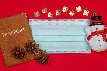 Protective surgical mask and passport with christmas decorations over red background. Christmas holidays and travel  concept. Coronavirus, covid-19. Copy space. Space for text.