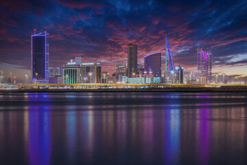 Fototapeta na wymiar The sun set modern city skyline with neon lights and reflection in the water. Manama, the Capital of Bahrain, Middle East