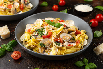 White shell clams in Garlic and parsley white wine sauce tagliatelle pasta served with cherry tomatoes and parmesan cheese