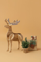 Wooden reindeer with small Christmas tree and presents on beige background