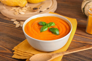Bowl with delicious pumpkin cream soup on wooden background, closeup