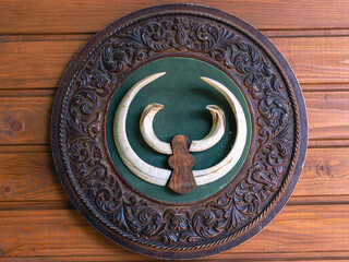 A symbolic image on the wall. Antique carved wooden symbol with animal horns. A symbolic sign in the Caucasus.