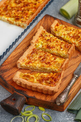 Freshly baked homemade onion pie stuffed with leeks, eggs and cheese on a wooden board. Tart. quiche. Homemade pastries for gourmets. Breakfast. Brunch. Selective focus