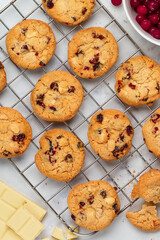 Freshly baked homemade cookies with white milk chocolate and cranberries on a marble background. A festive treat. The concept of home baking. Selective focus, top view