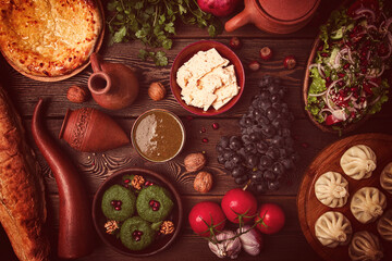 Fototapeta na wymiar Traditional Georgian table, top view, Khinkali, Phali, Shoti, Khachapuri, Sauces, Fruits, nuts, Salad, cheese, horizontal, no people,