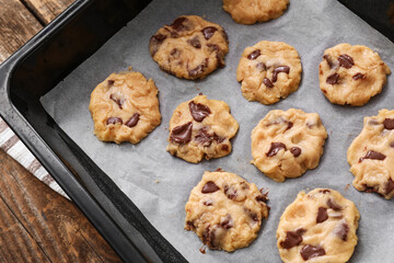 Baking tray with uncooked cookies on wooden background