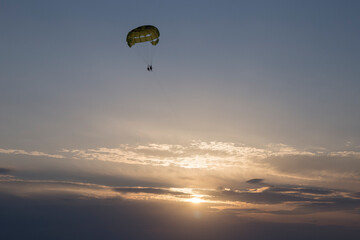 two tourists parasailing over
the sea during sunset
