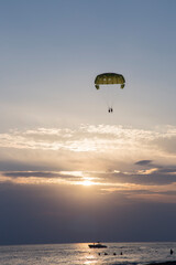 two tourists parasailing over
the sea during sunset