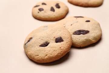 Delicious homemade cookies with chocolate chips on beige background, closeup