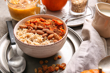 Bowl of tasty oatmeal with pumpkin and almond on table