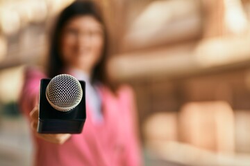Middle age reporter woman holding journalist mic close to the camera, close up of professional microphone.