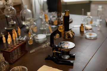 Fototapeta na wymiar Vintage old microscope on table for science background. Medicine, alchemy, pharmacist. glass jars, flasks and tools, Selective focus