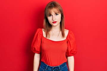 Redhead young woman wearing casual red t shirt relaxed with serious expression on face. simple and natural looking at the camera.