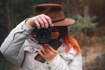 Obraz premium woman with a camera taking photos in the forest. Dressed leather hat and yellow sunglasses. Autumn day