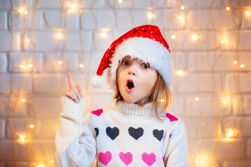 A girl in a New Year's hat raises her thumbs up enthusiastically. Oh, idea