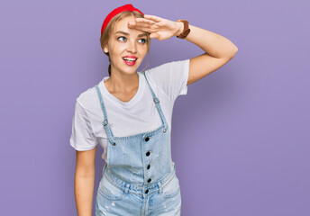 Young caucasian girl wearing casual clothes very happy and smiling looking far away with hand over head. searching concept.