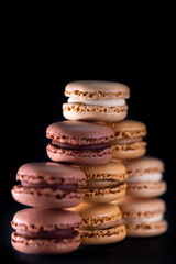 chocolate, coffee, vanilla, lemon and strawberry macaroons on black background