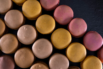chocolate, coffee, vanilla, lemon and strawberry macaroons on black background