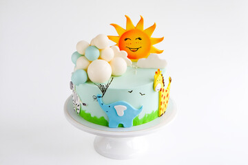 Baby birthday cake decorated with sun, clouds, elephant, giraffe, zebra animal figurines and...