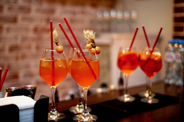 Alcoholic cocktail of orange color with red tubes. Work as a bartender in a nightclub.