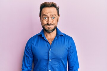 Middle age man wearing casual clothes puffing cheeks with funny face. mouth inflated with air, crazy expression.