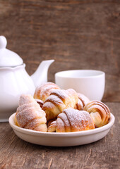 Cookies bagels with jam in powdered sugar in a plate on a dark background.