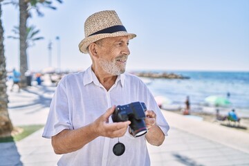 Senior man smiling confident wearing summer hat using camera at seaside