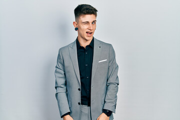 Young caucasian boy with ears dilation wearing business jacket winking looking at the camera with...