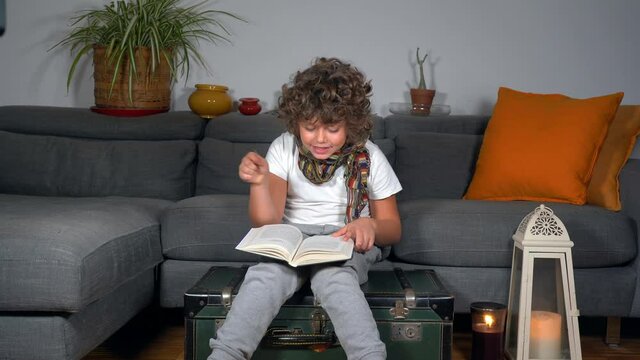 Europe, Italy , Milan November 2021 - Boy 7 years old read Harry Potter book ( the philosopher's Stone ) making magic spells with the wand of power in the house - lifestyle in apartment childhood 