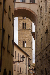 Gassen und Gebäude und Kirchturm mit Durchblick  in Volterra bei bewölktem Himmel 