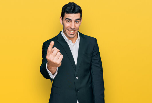 Handsome hispanic man wearing business clothes beckoning come here gesture with hand inviting welcoming happy and smiling