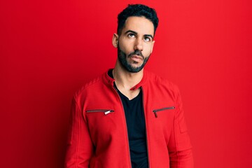 Young hispanic man wearing red leather jacket making fish face with lips, crazy and comical gesture. funny expression.