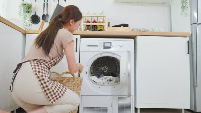 Asian beautiful woman put dirty clothes to washing machine in house.	