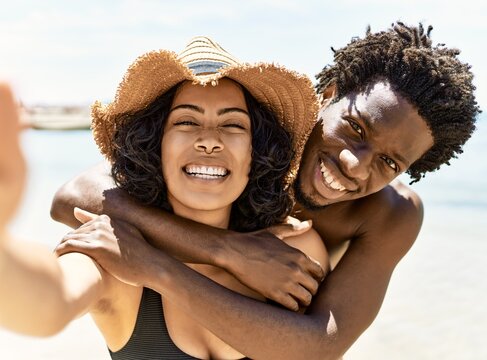 Young interracial tourist couple wearing swimwear make selfie by the camera at the beach.