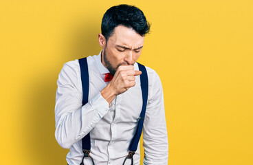Hispanic man with beard wearing hipster look with bow tie and suspenders feeling unwell and coughing as symptom for cold or bronchitis. health care concept.