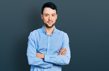 Hispanic man with beard with arms crossed gesture relaxed with serious expression on face. simple and natural looking at the camera.