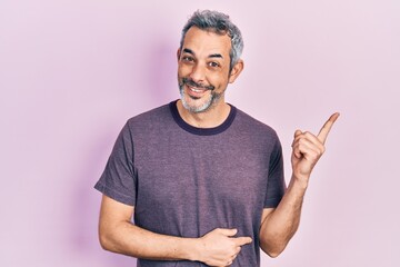 Handsome middle age man with grey hair wearing casual t shirt smiling happy pointing with hand and finger to the side